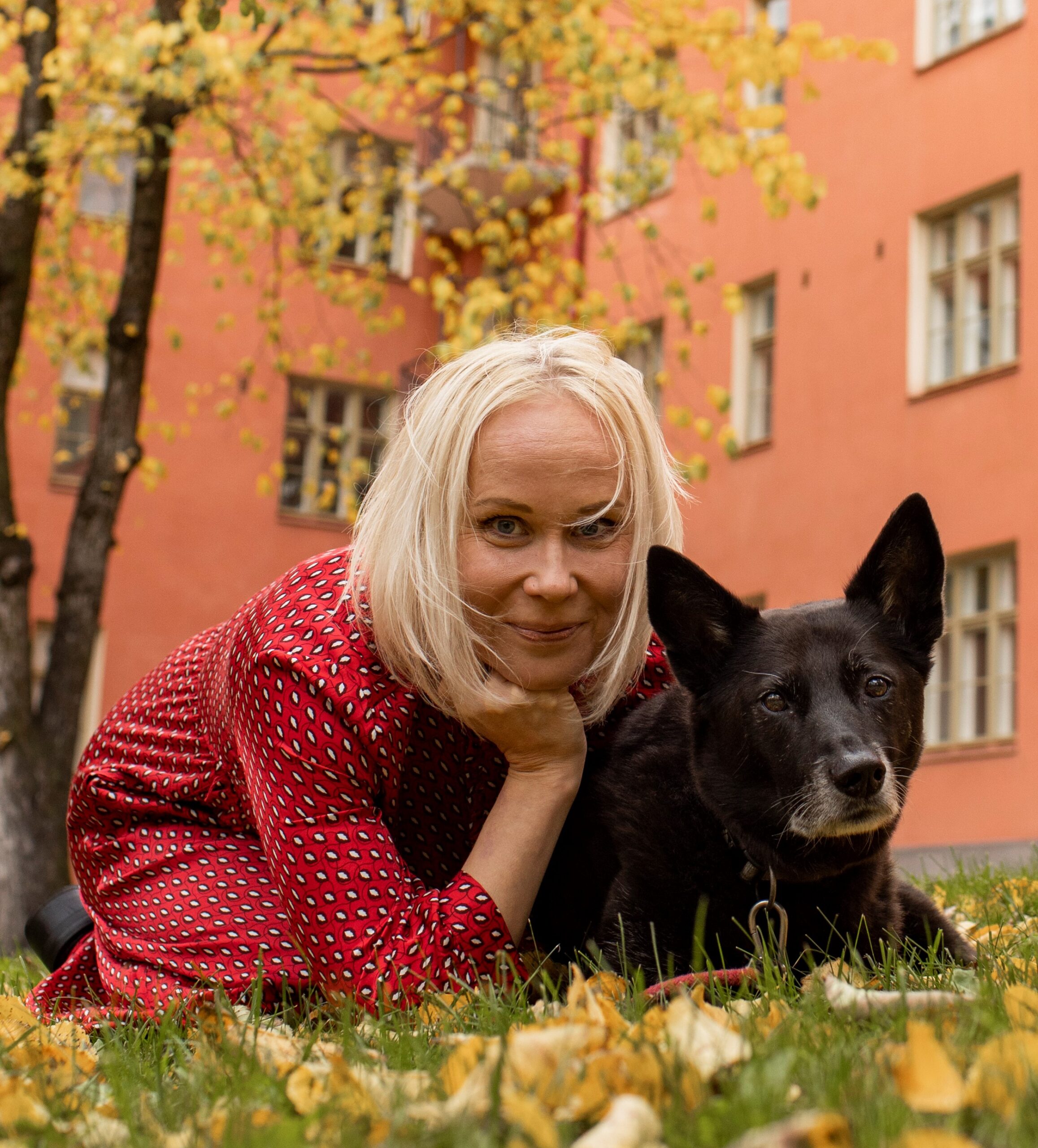 Elisa Aaltola ja koira nurmikolla, taustalla talo for 